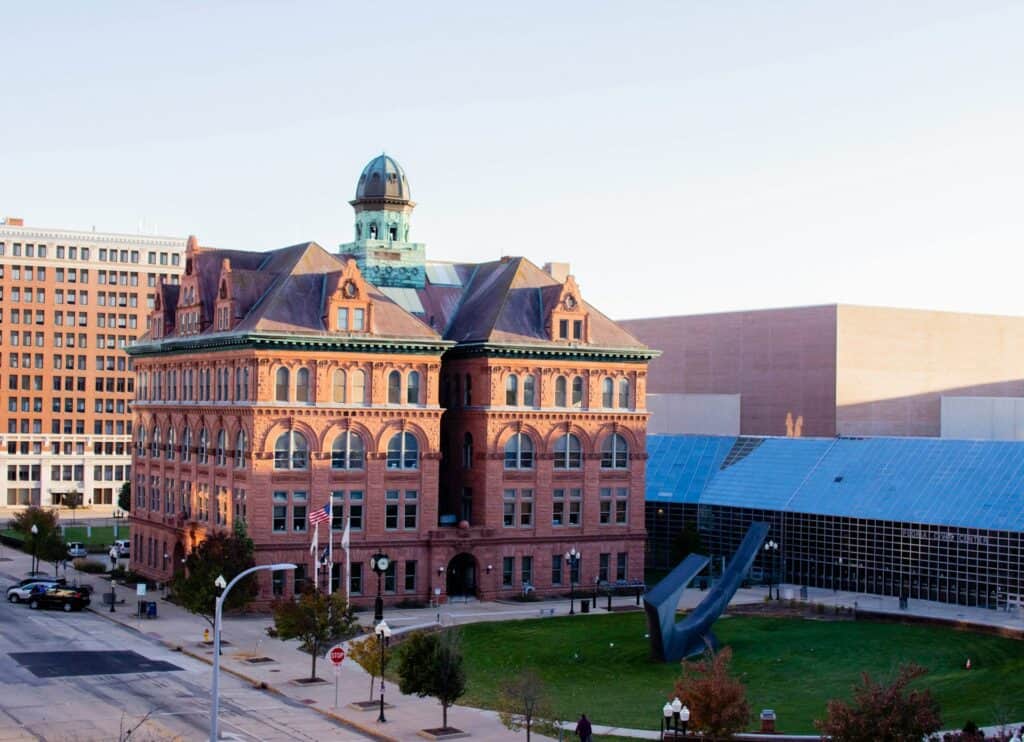 Historic courthouse with a green dome and red brick facade in downtown cityscape.