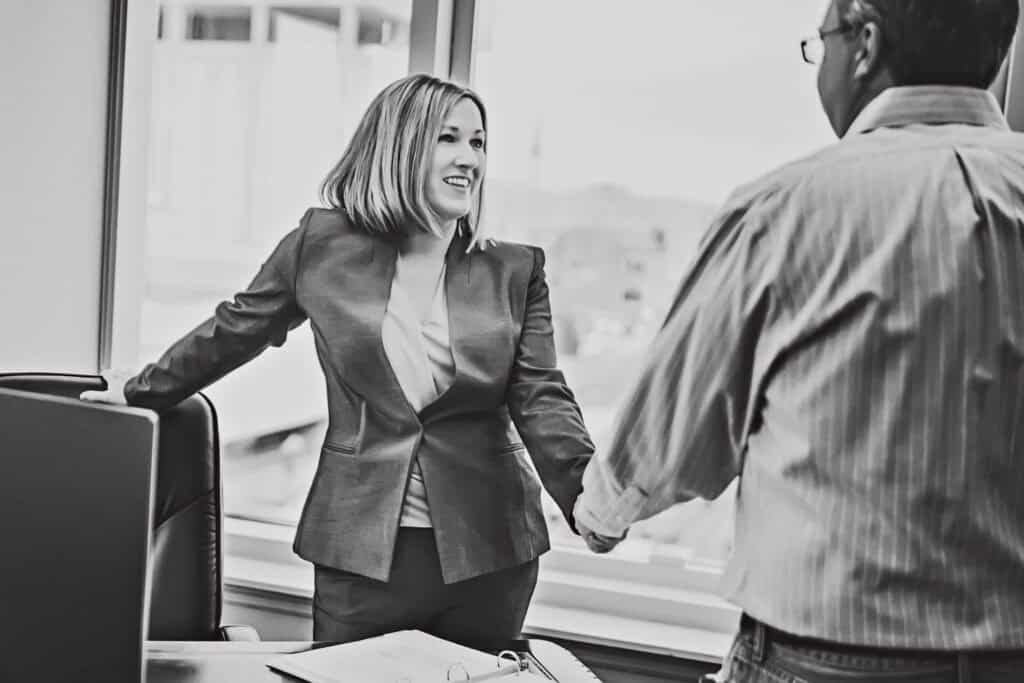 Kaitlin McMillan shaking hands with a client in a professional office setting.