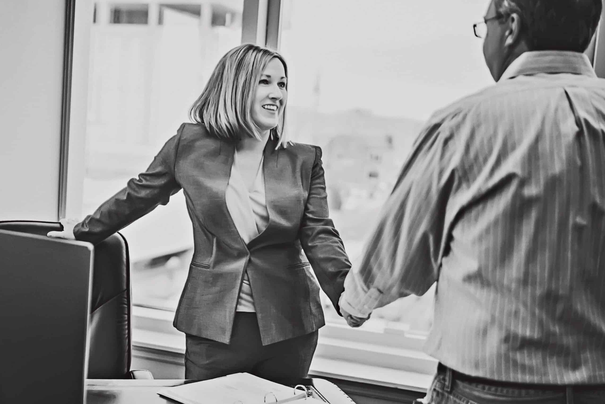 Kaitlin McMillan shaking hands with a client in a professional office setting.