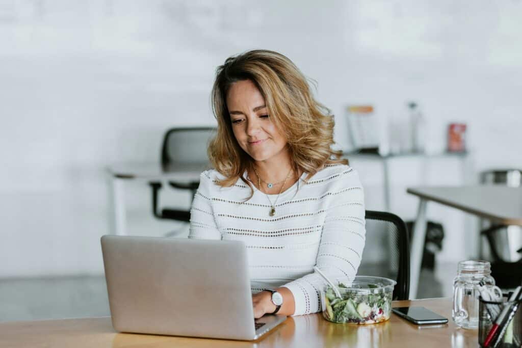 Woman working on laptop at desk, legal documents on table, legal advice for prenups.